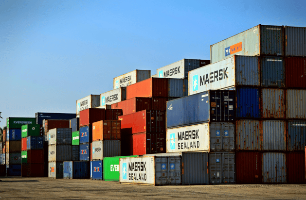 Colorful shipping containers stacked high at a port yard under a clear blue sky