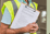 Person in a high-visibility vest holding a clipboard with a home inspection checklist