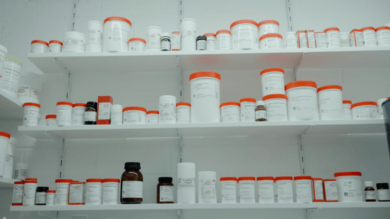A shelf with lots of white and orange medication bottles.