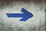 Blue arrow painted on a weathered concrete surface pointing to the right.