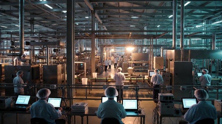 A food and beverage factory floor with workers monitoring production operations through connected devices.