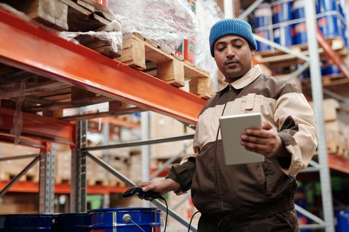A manufacturing floor worker using a tablet to complete a digital inspection checklist.