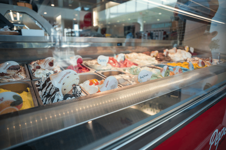 A commercial freezer displaying different ice cream flavors.