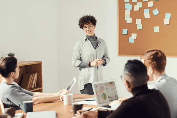 Woman presenting to colleagues at a conference table in an office meeting.