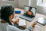 Young student with braided hair attending a video call on a laptop with teacher giving thumbs up on screen.