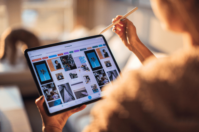 Person holds tablet and stylus while browsing a gallery of design templates in an app.