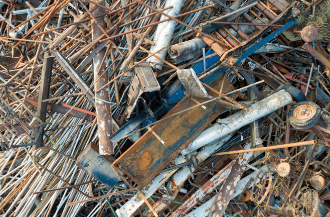 A large pile of rusty scrap metal including pipes, rods, beams, and old machinery parts.