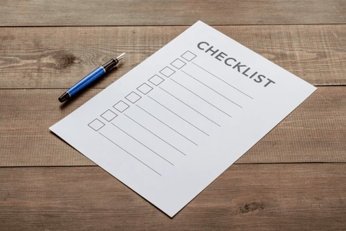 A paper checklist with a pen on a wooden surface. (Image courtesy of Shutterstock)