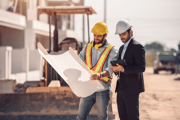 Construction worker in a safety vest and a project manager in business attire.
