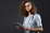 Female nurse in scrubs and glasses holding tablet device.
