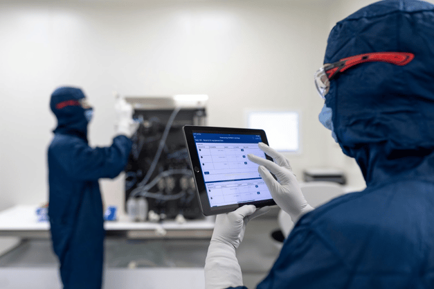 Healthcare workers in surgical masks and scrubs using tablets in a medical facility.