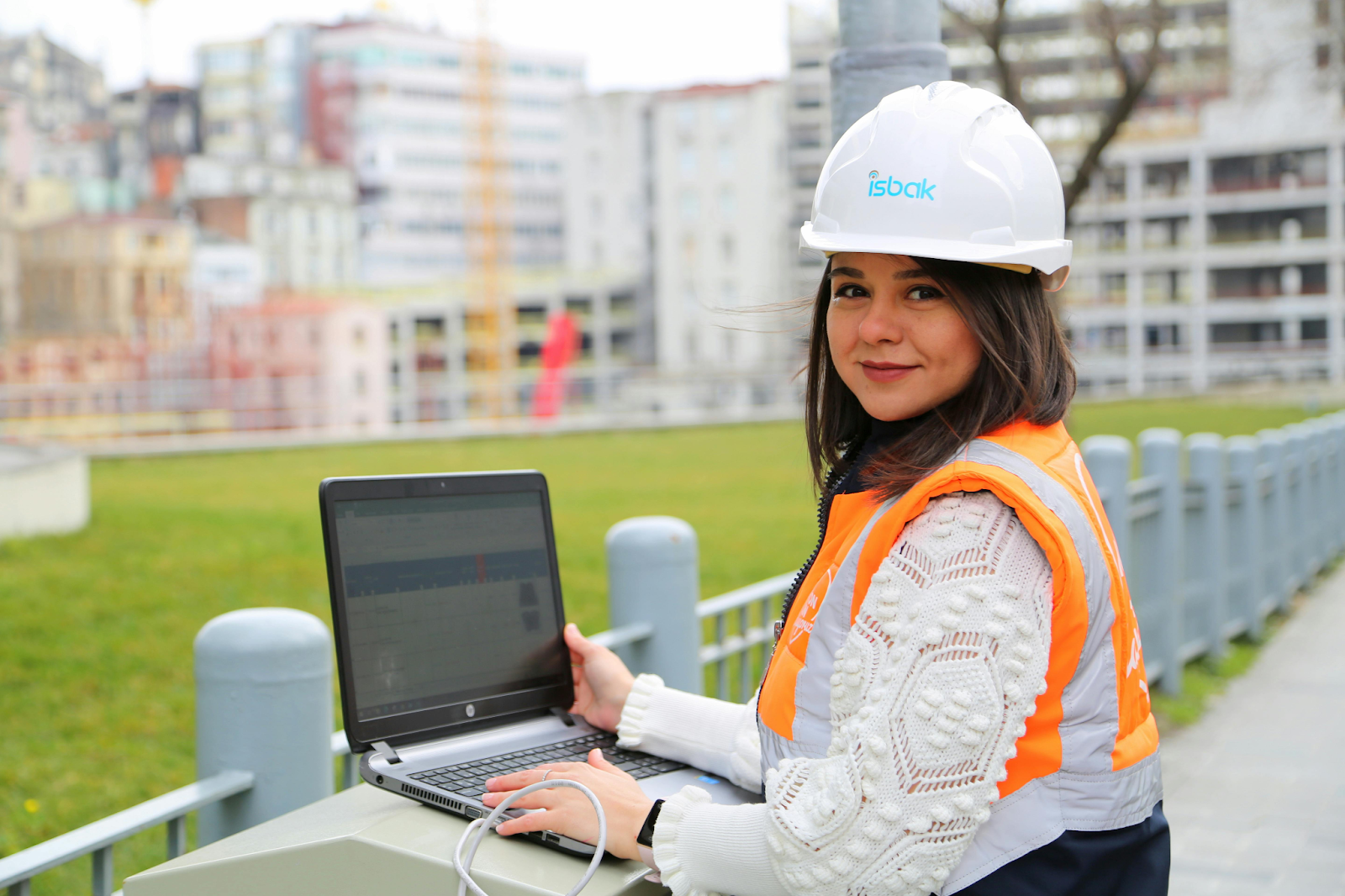 Engineer using a laptop at an outdoor construction site.