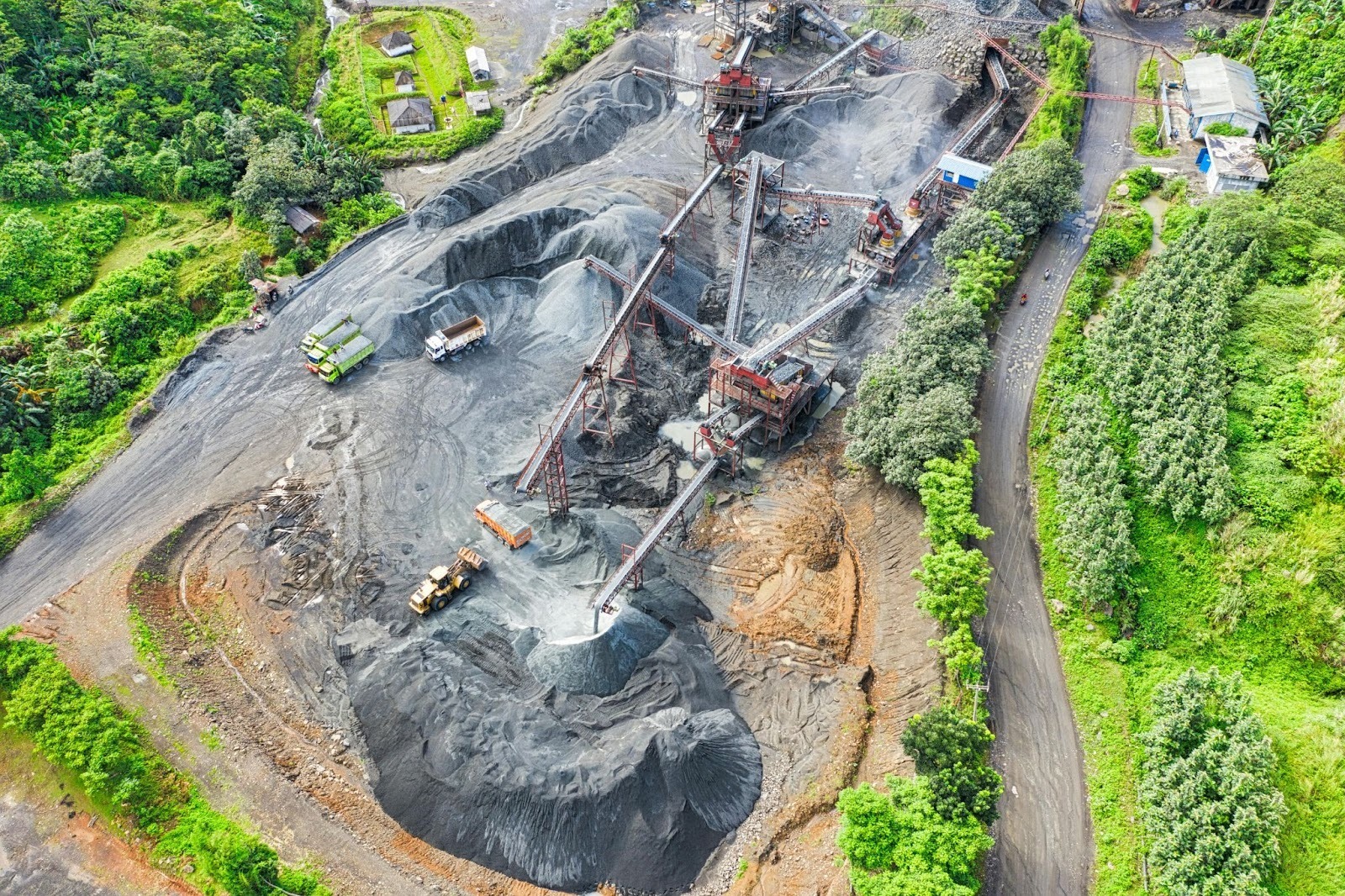 An aerial view of a quarry in the middle of a forest with heavy machinery