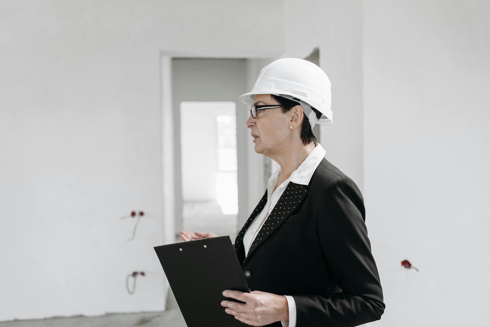Female construction inspector reviewing a building site with a clipboard.