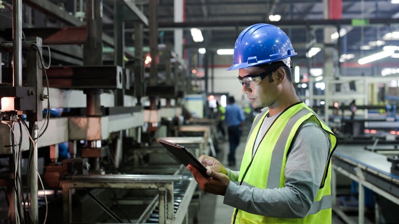 Manufacturing worker using a tablet on the shop floor to manage production scheduling
