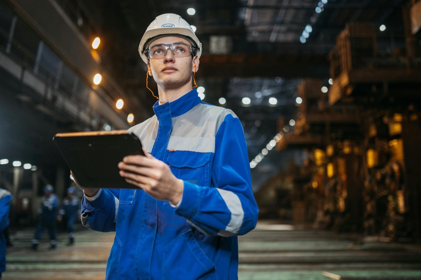 Manufacturing technician using a tablet to complete a digital quality inspection on the production floor.