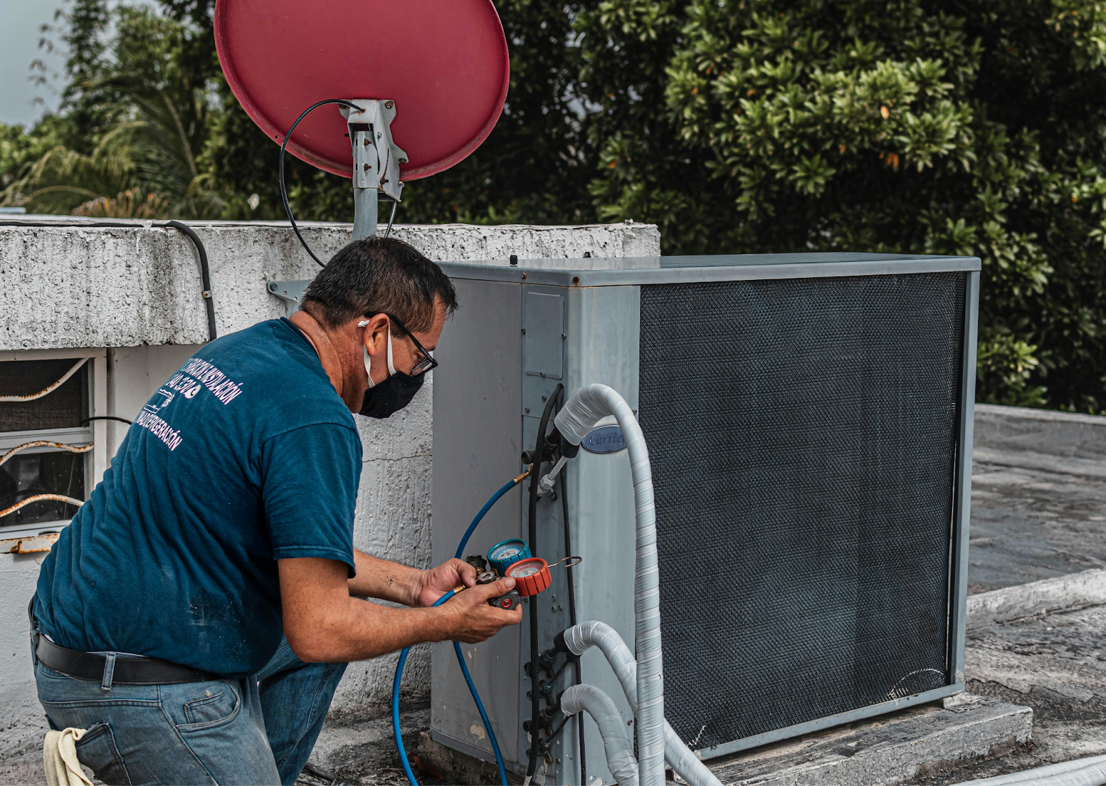 HVAC technician servicing an outdoor AC unit on a rooftop.