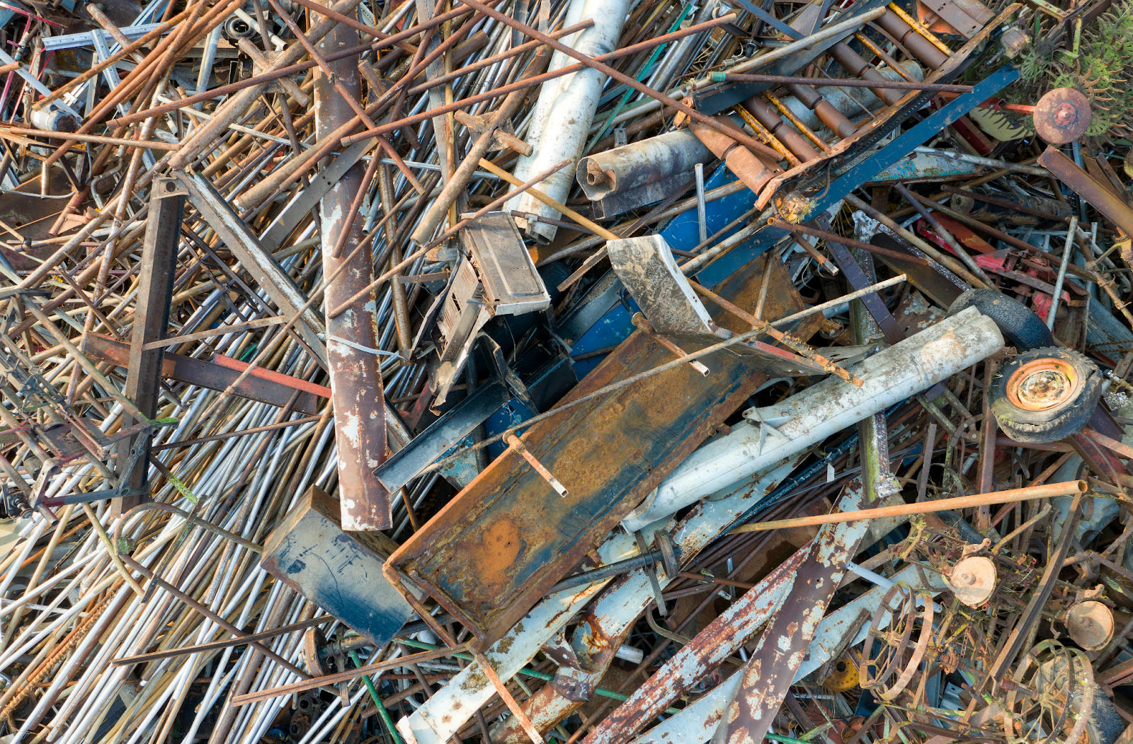 A large pile of rusty scrap metal including pipes, rods, beams, and old machinery parts.